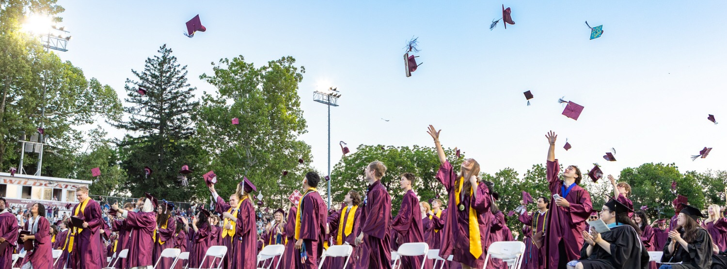 Grads toss their caps in the air.