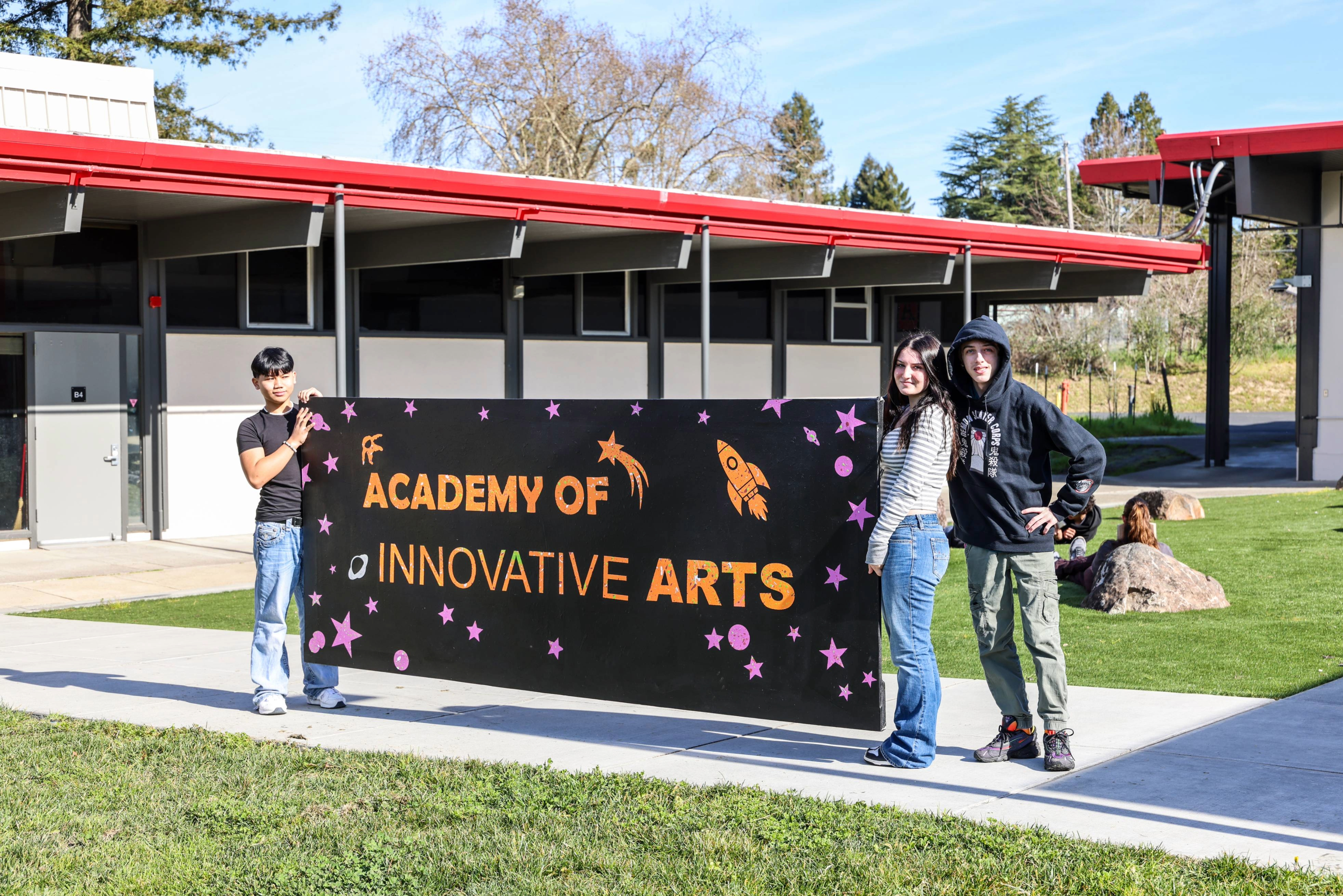 Academy students holding up their school sign