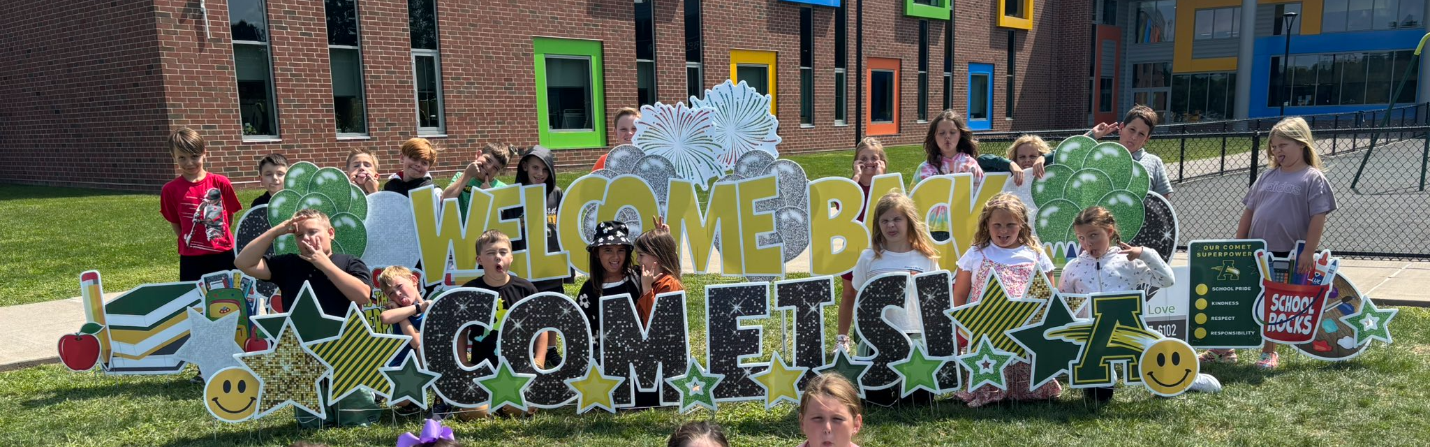 Students posing in front of the welcome back to school sign 