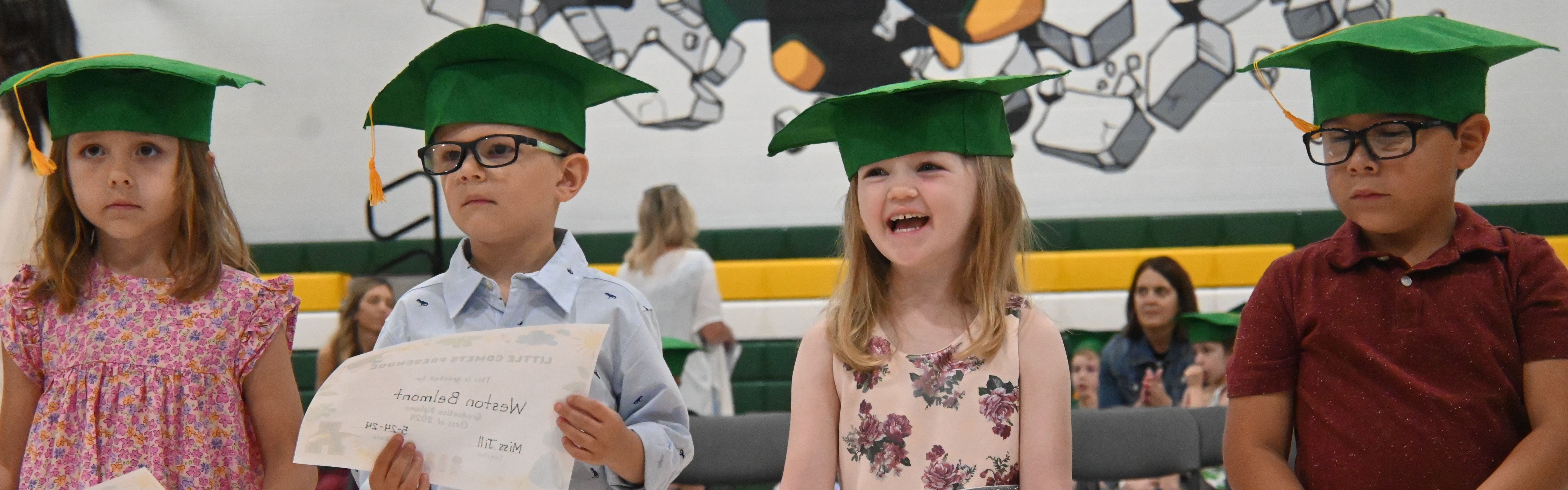 Students receive their preschool graduation diplomas