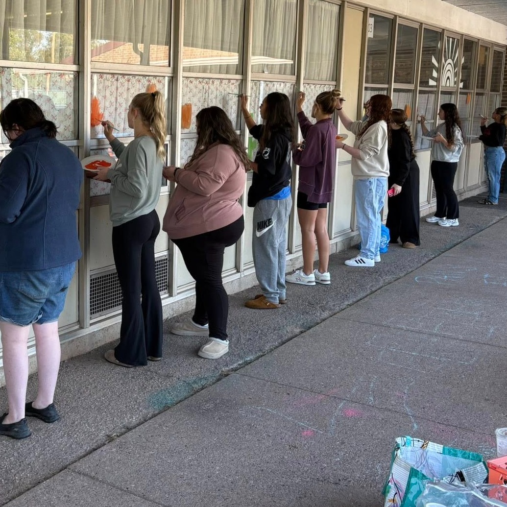 nitro high school art students painting windows at nhs feeder school point harmony elementary.