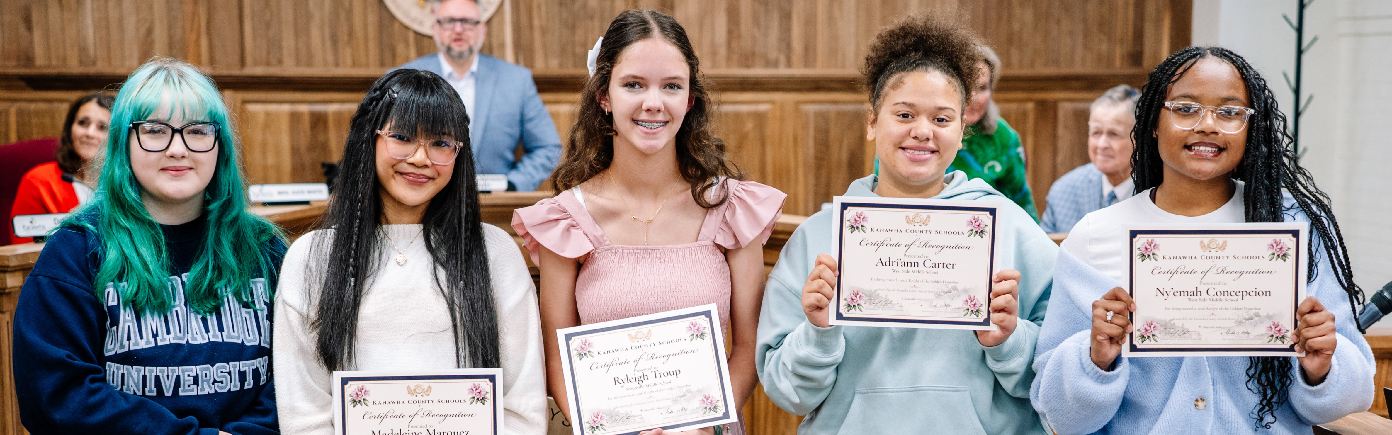 Five eighth grade students posing for a picture in the KCS Board Room. The students are holding certificates for earning the 2026 Golden Horseshoe. 