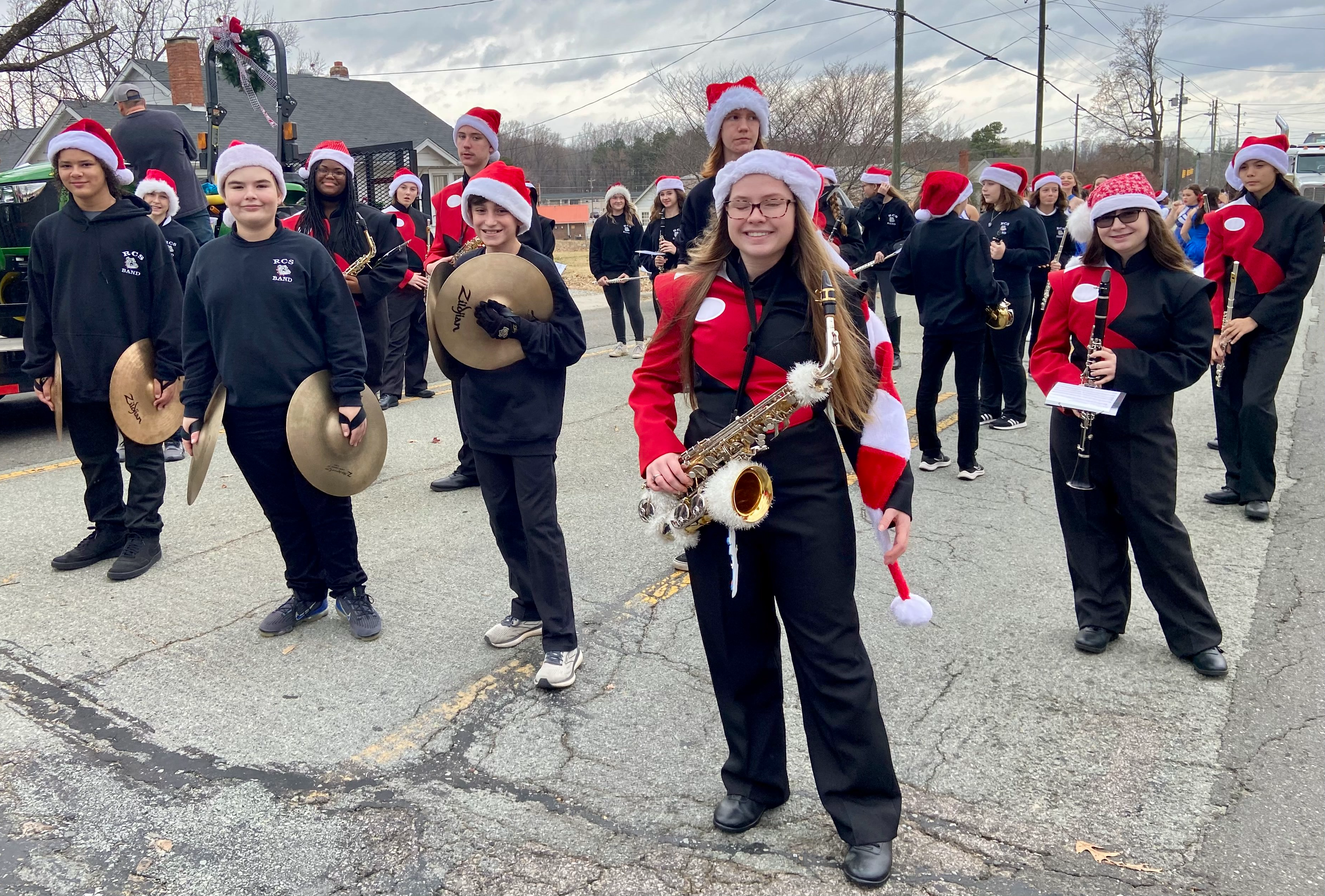 Student Marching Band members hold their instruments, wear santa hats and prepare for the parade