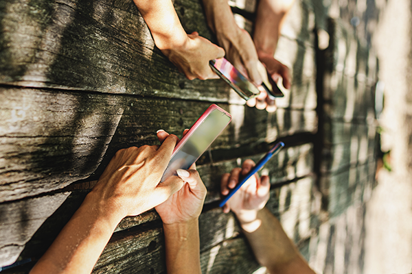 hands holding cell phones on a picnic table