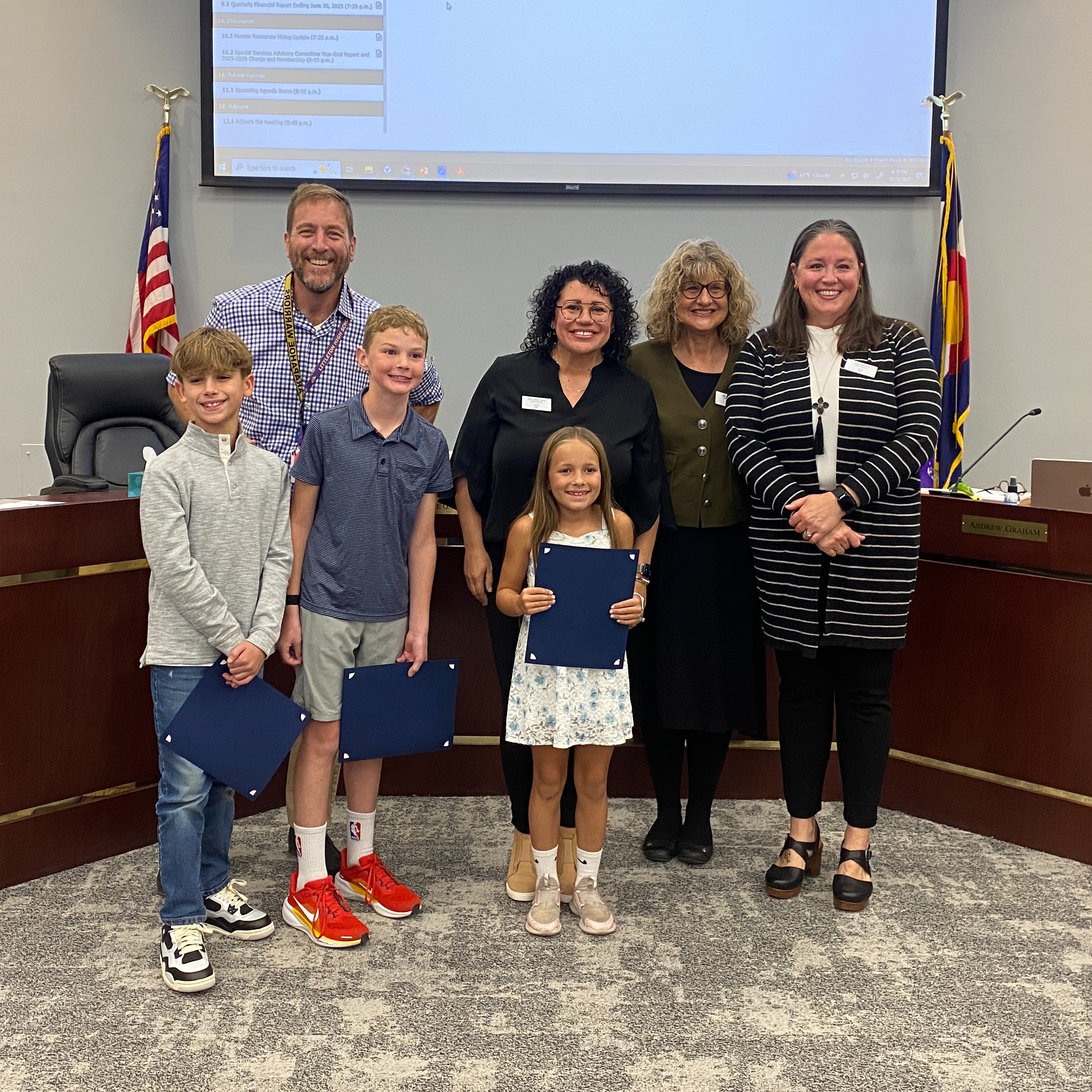 Three students from Wilder stand with Board of Education members in the LPS Boardroom.