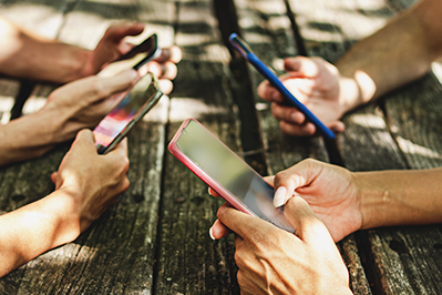 hands holding cell phones on a picnic table