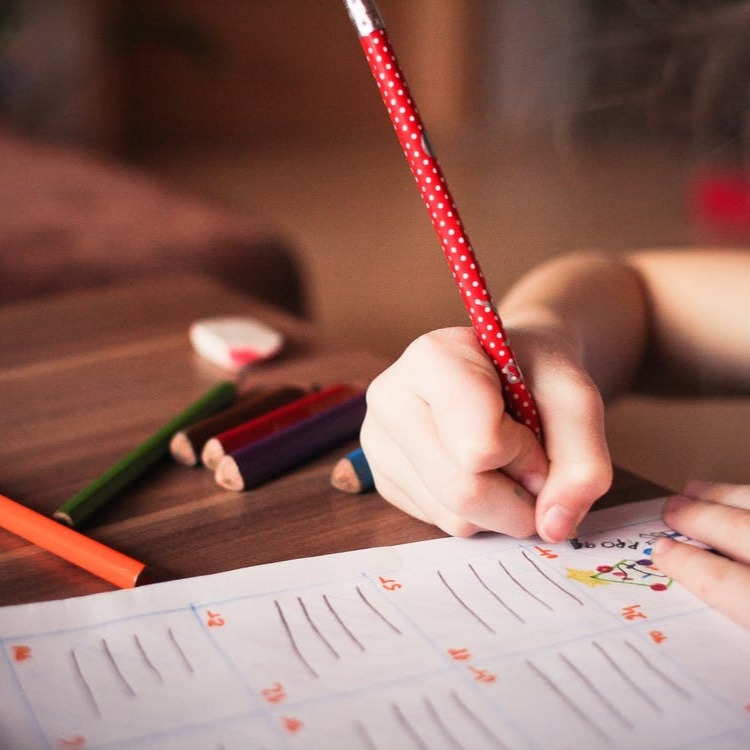 student writing with a red pencil