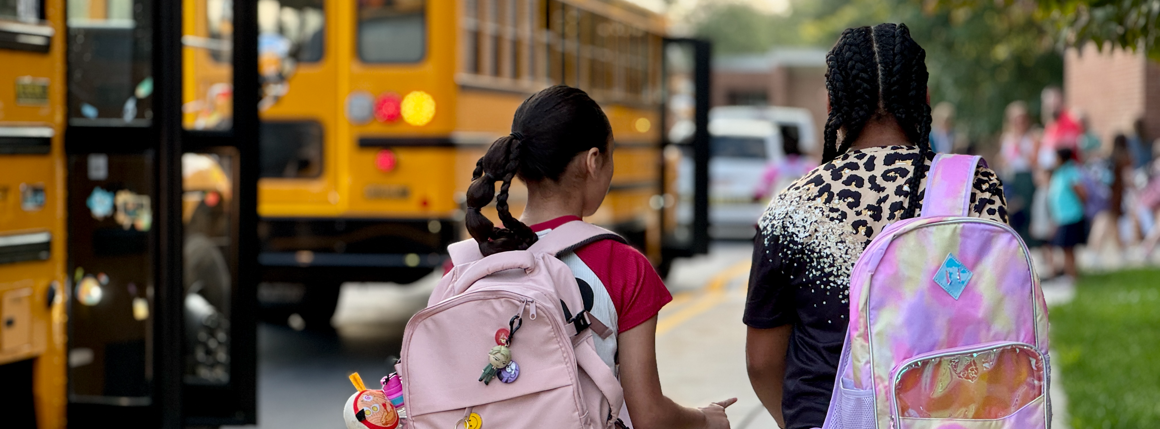 Two students walking toward school bus.