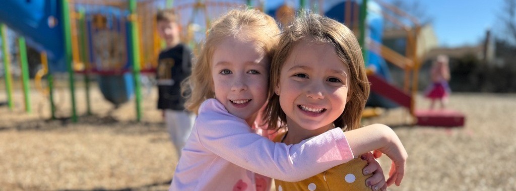 Two smiling little girls on the playground.