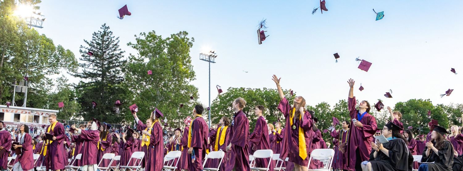 Grads toss their caps in the air.