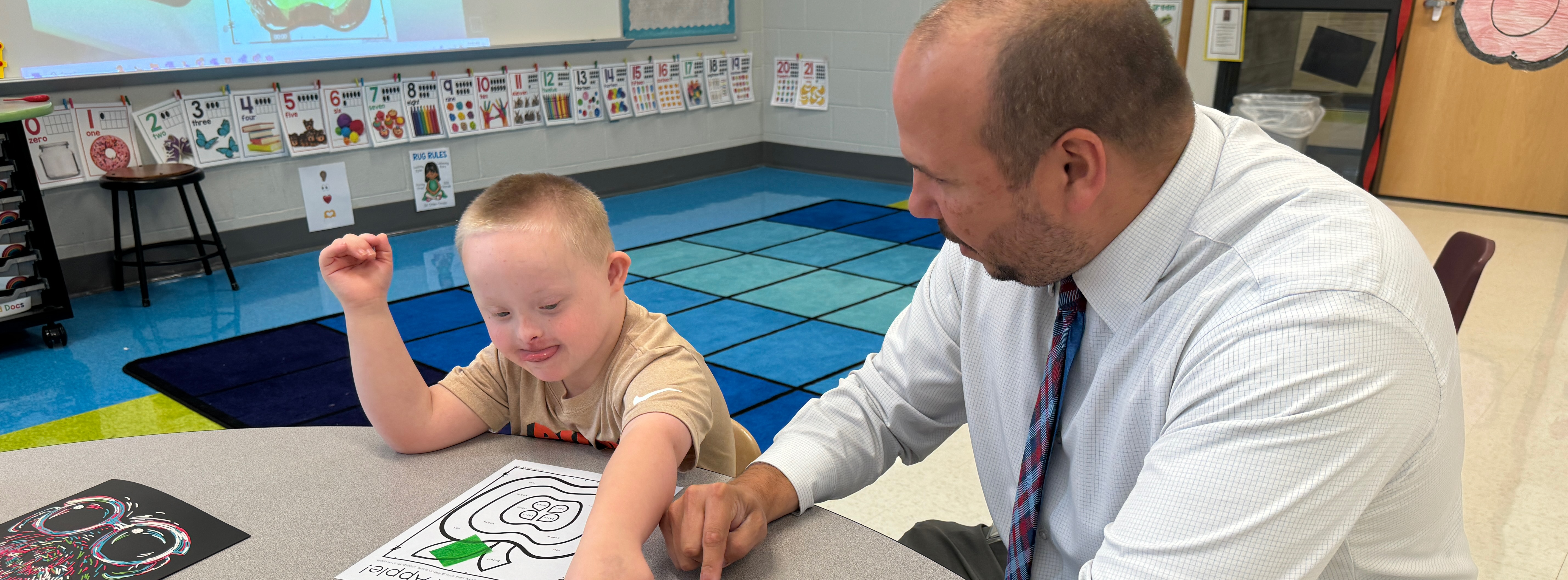 An adult helping a student with a class project.