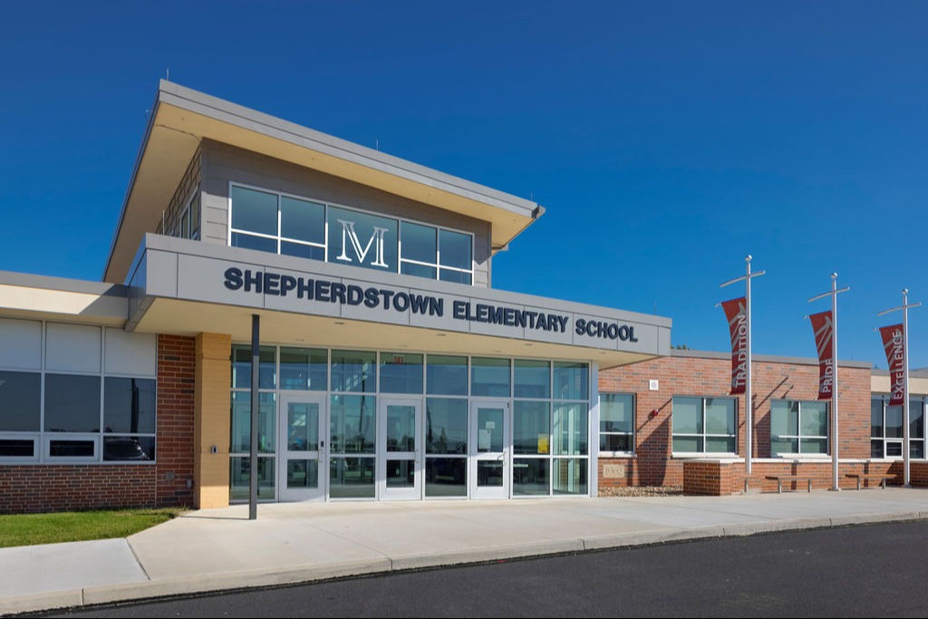 A large brick building with multiple windows and a solid structure, set against a clear blue sky.