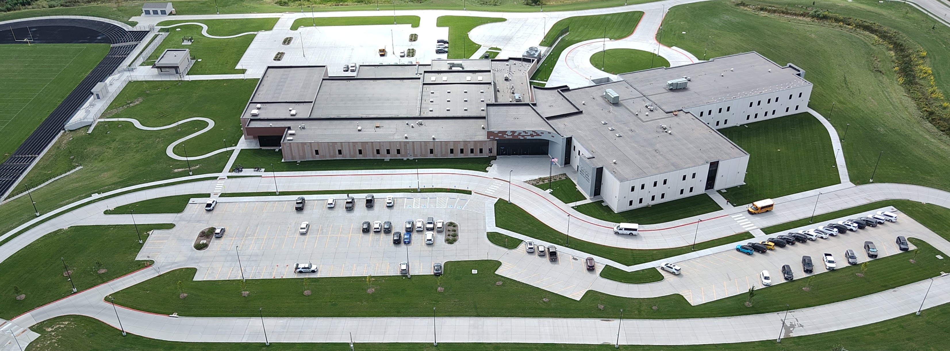 an aerial view of the middle school including parking lot and football field