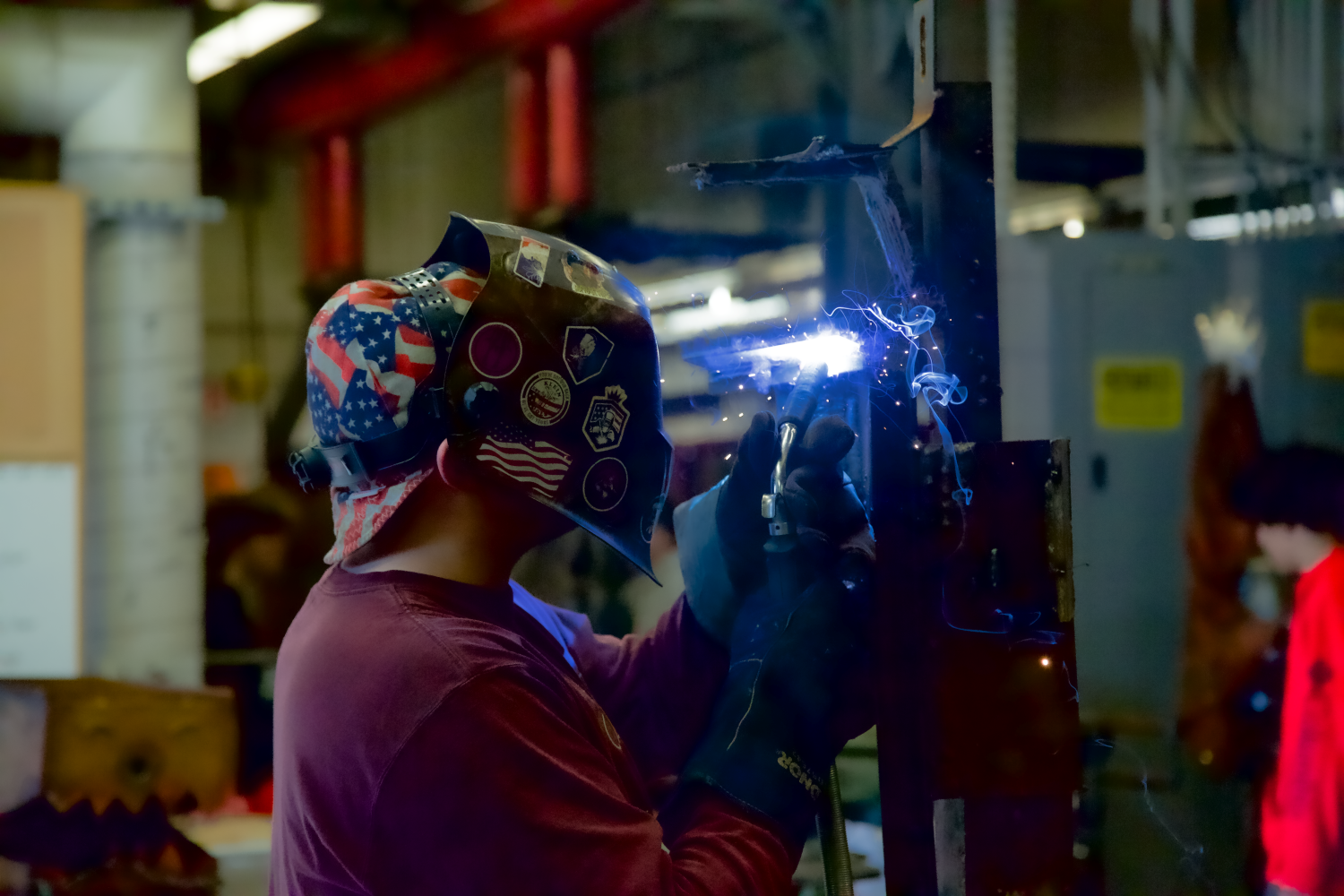 The student wearing a welding helmet and welding