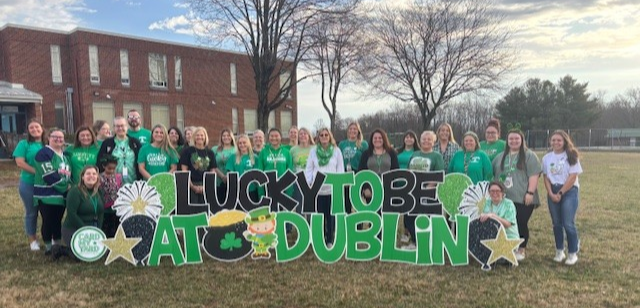 Dublin staff smiling in schoolyard in green shirts.