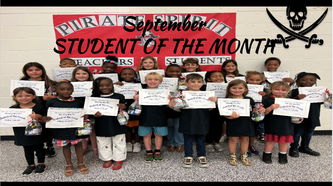 A group of children holding certificates stands in front of a banner that reads 'September Student of the Month' with a pirate theme.