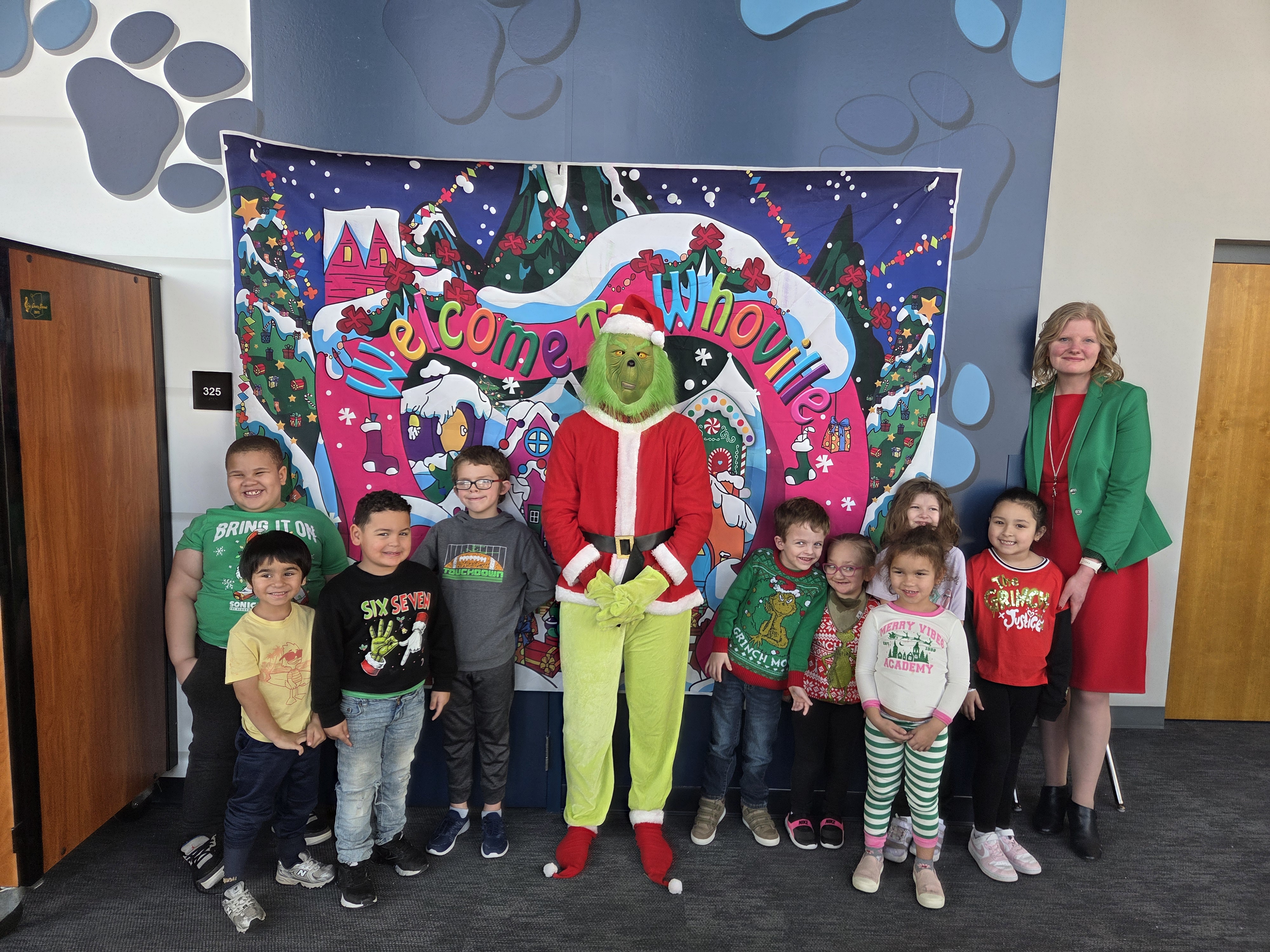students pose with the grinch and their superintendent