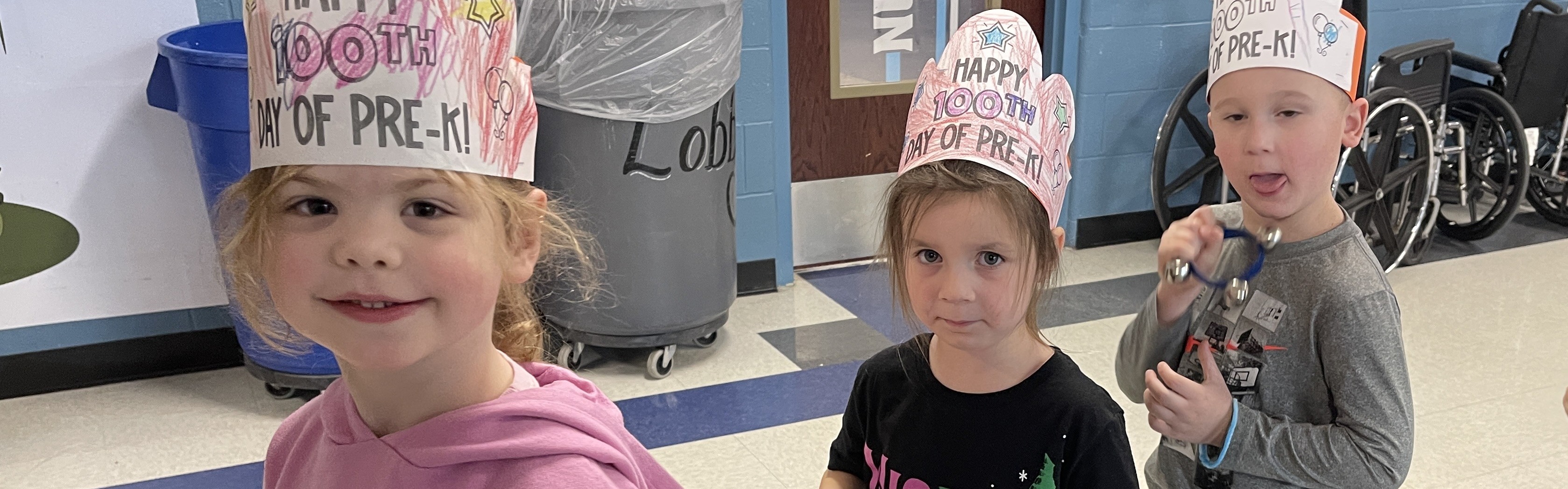 students smile as they walk in parade through school hallways wearing 100 day crowns