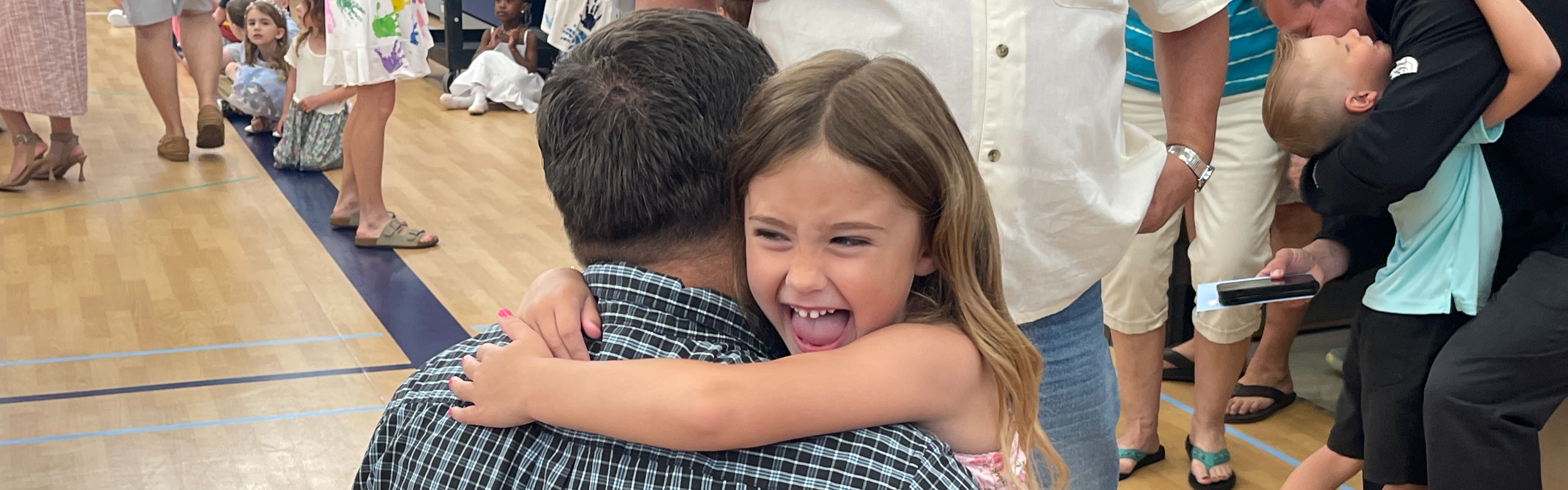 child smiles as she hugs her family member after graduation