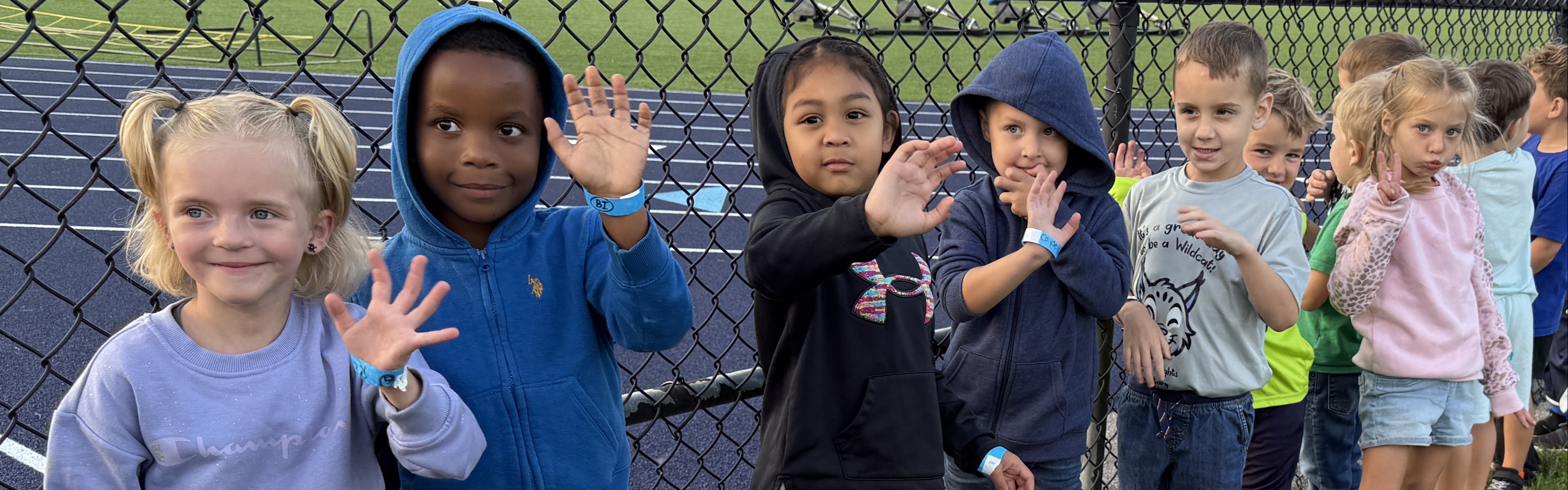 students lined up along face smiling and waving