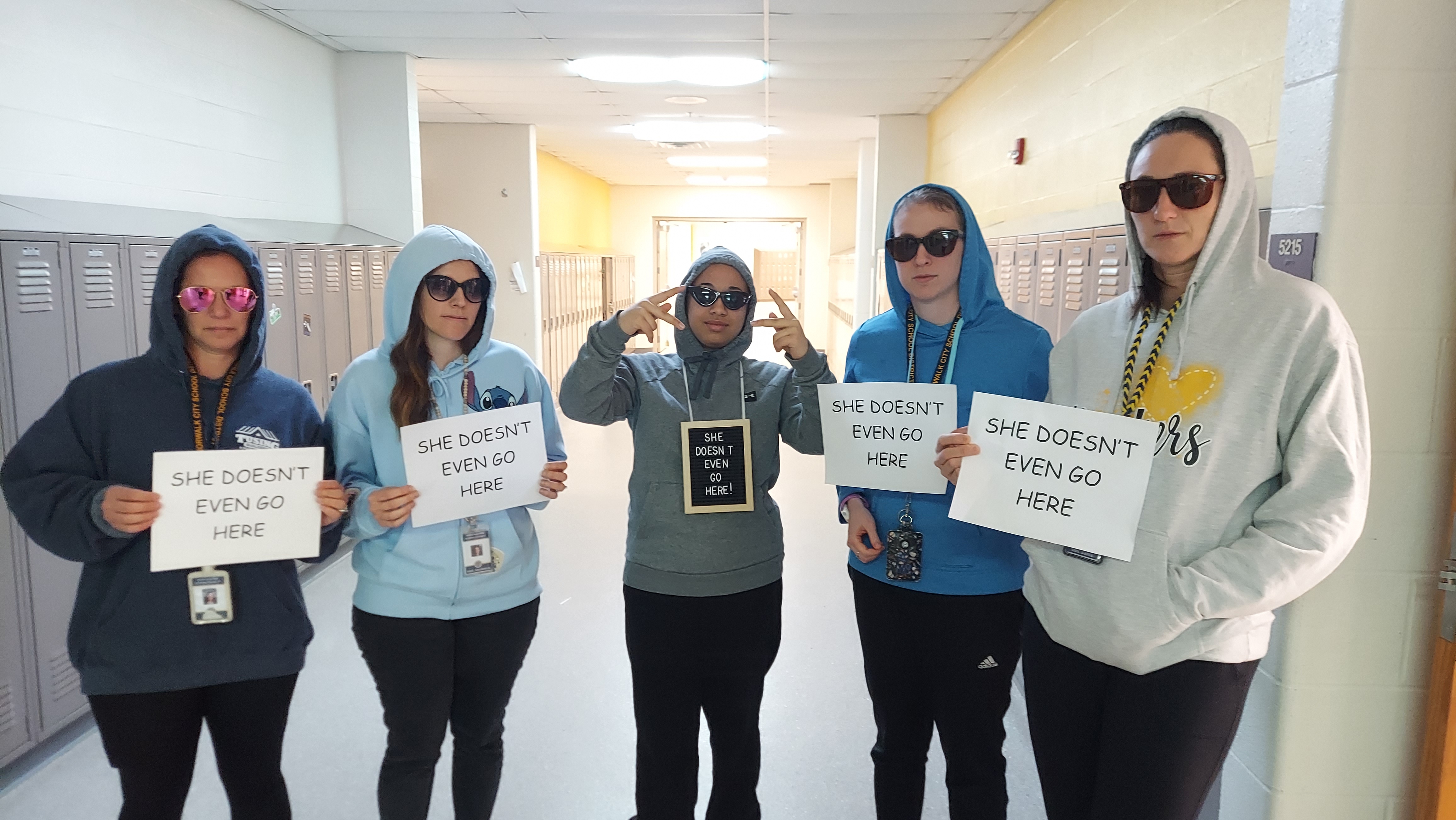 teachers with hoodies on holding signs