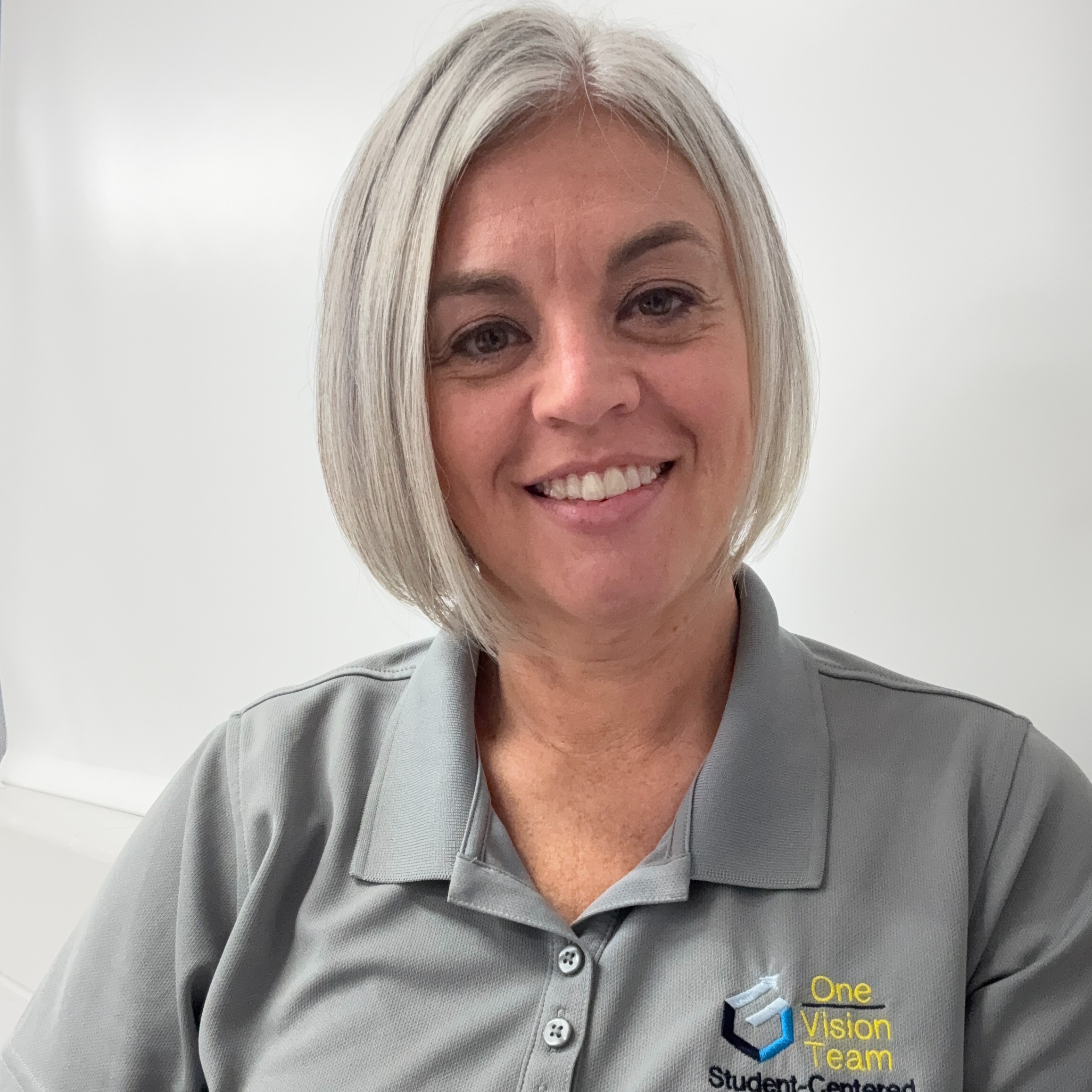 Woman in grey shirt with short grey hair smiling