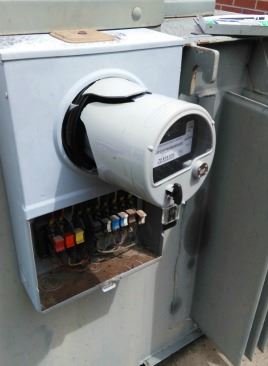 Close-up view of a meter and electrical box, showcasing the dials and connections for monitoring electrical usage.
