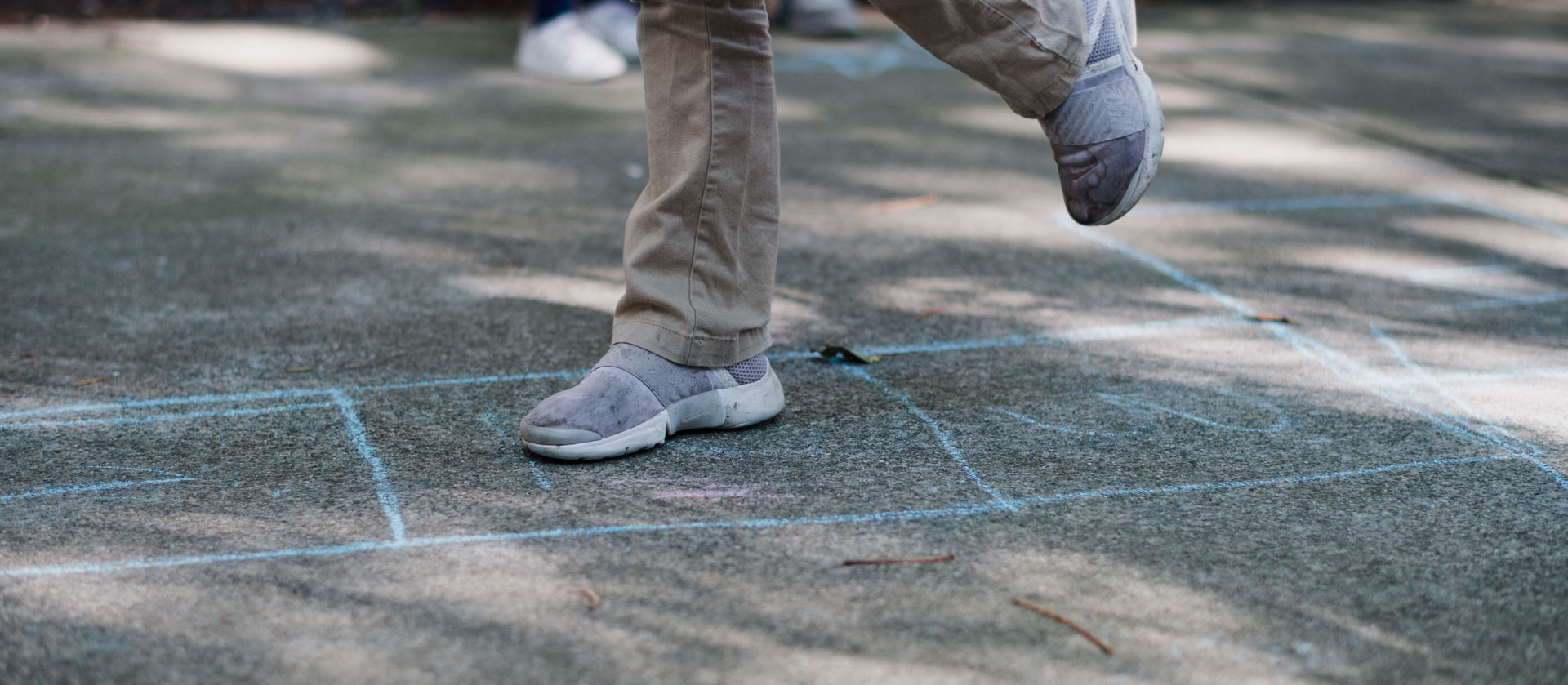 A person stands on a sidewalk, surrounded by colorful chalk drawings on the ground.