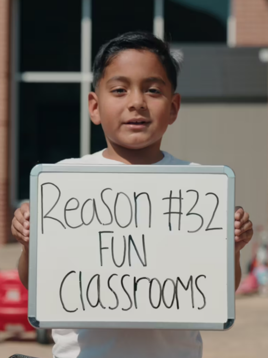 Male student holding sign that says Reason #32 Fun Classrooms