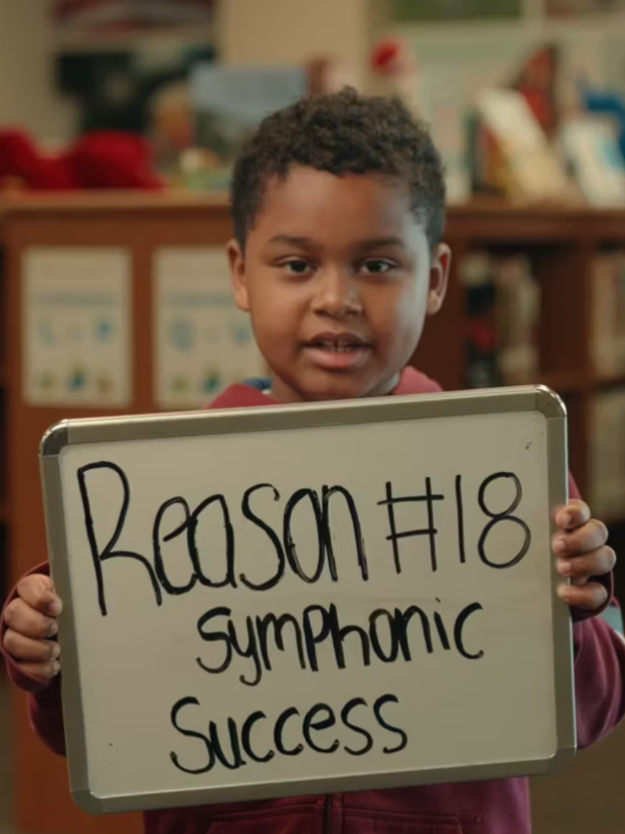 Male student holding sign that says Reason #18 Symphonic Success