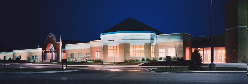 A well-lit commercial building at night, showcasing a modern architectural design with large windows and a prominent entrance.