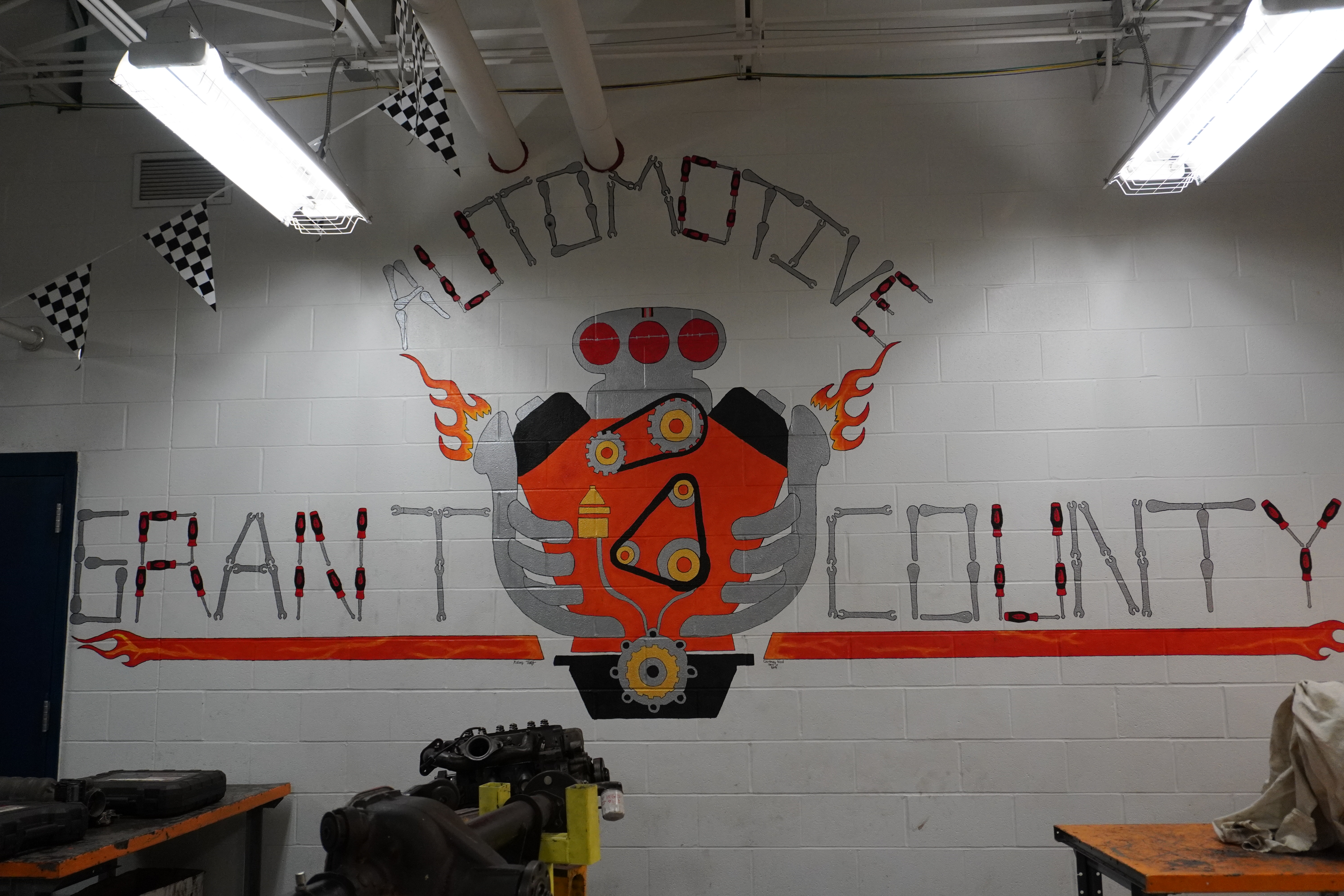 A mural on a wall featuring the words 'Automotive Grant County' with an illustration of an engine and decorative flames.