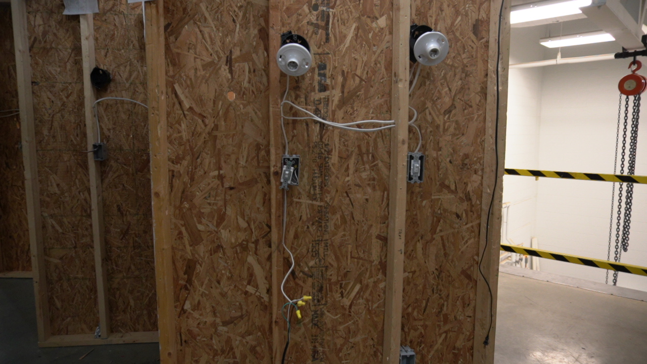 A view of wooden walls with electrical fixtures and wiring, indicating a construction or renovation site.