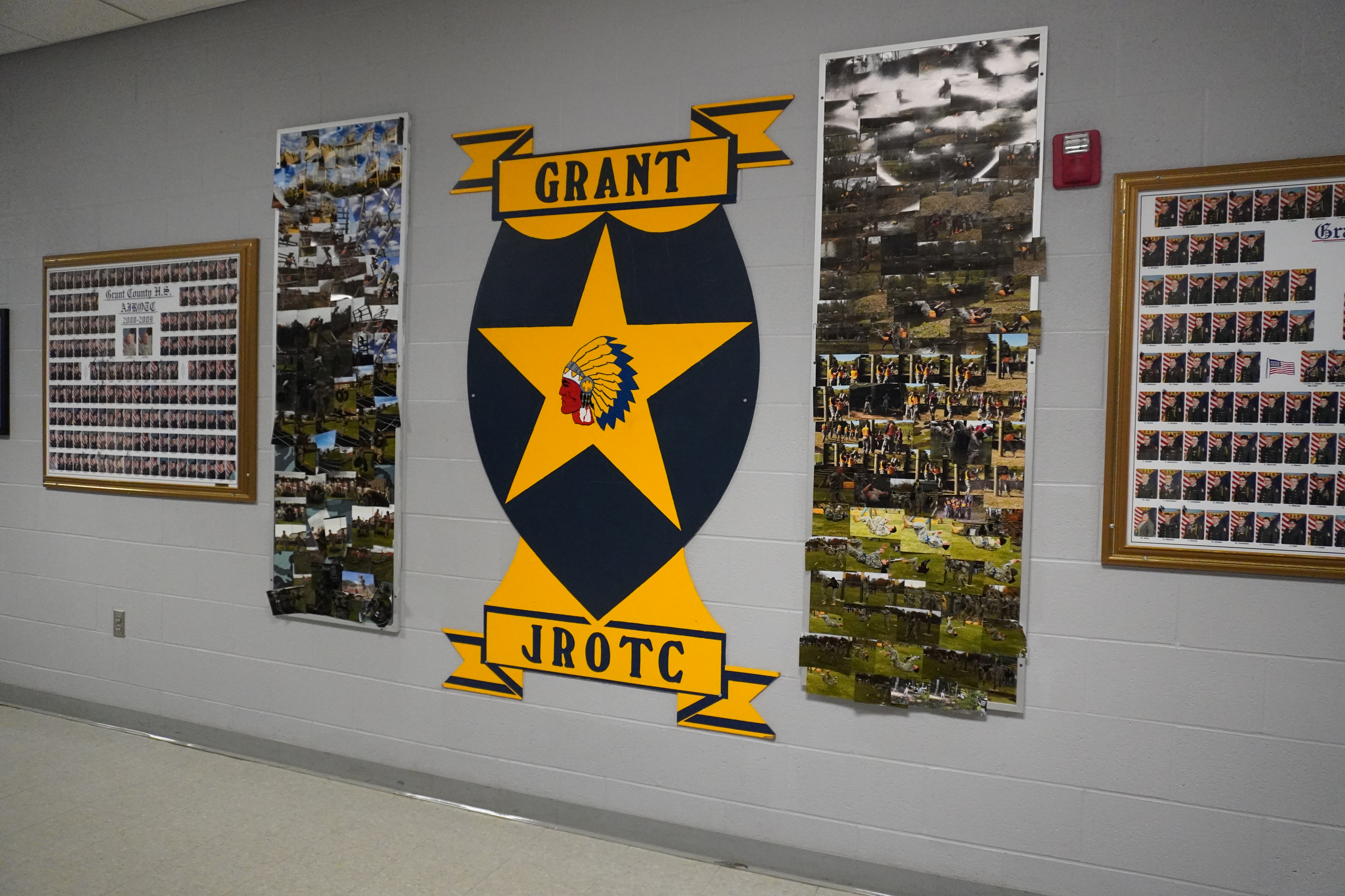 A wall display featuring the Grant JROTC emblem, which includes a large star and eagle design, surrounded by several photo collages showcasing JROTC activities and events.
