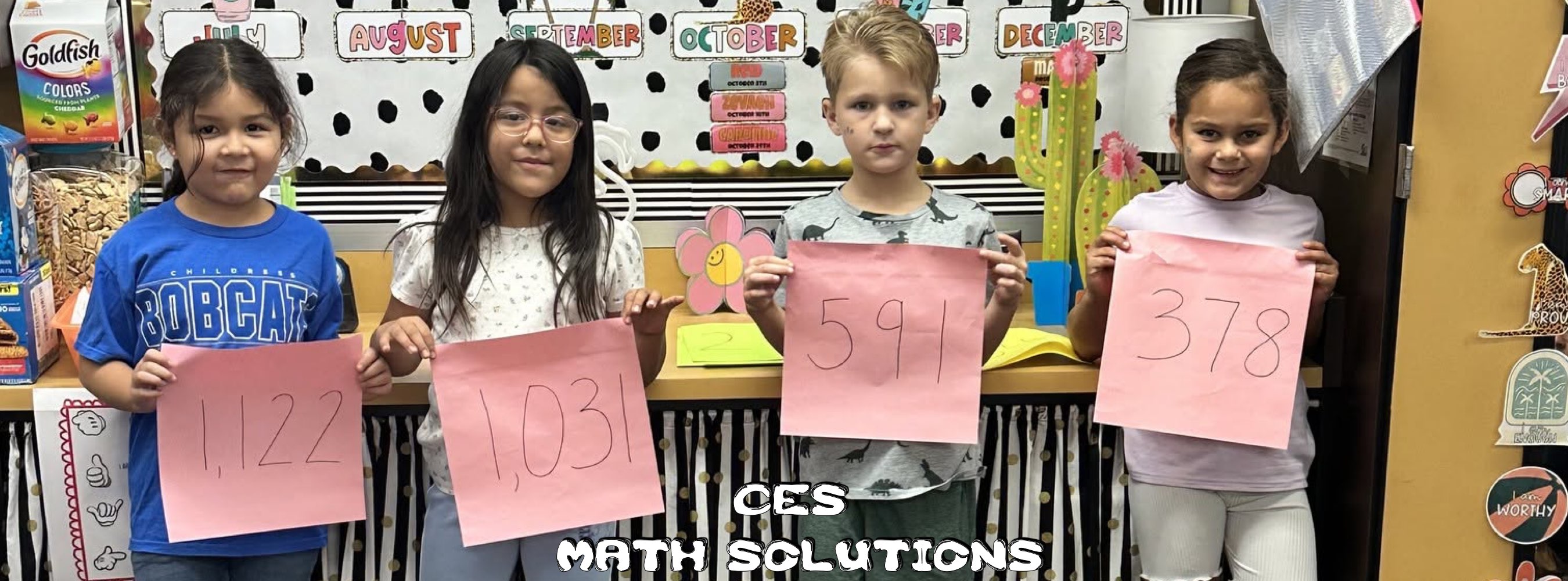 Five children in a classroom hold pink cards showing numbers 1,122, 1,031, 591, and 378, celebrating a cheerful math solutions activity.