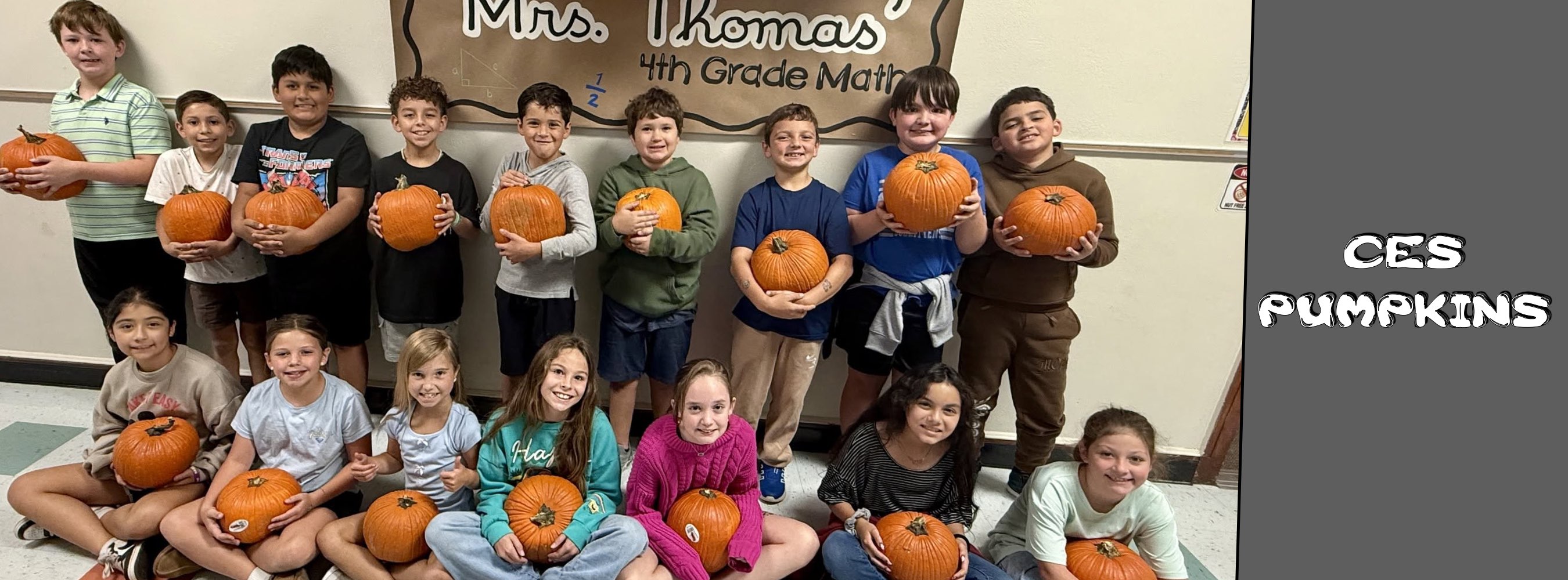 A cheerful fourth-grade class poses with pumpkins in front of a “Mrs. Thomas’ 4th Grade Mail” sign; “CES Pumpkins” appears beside them.