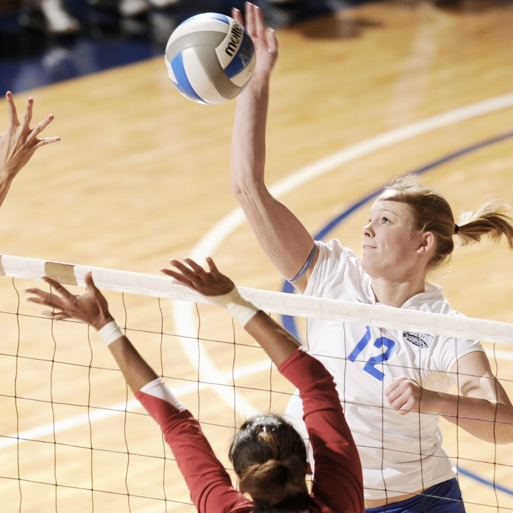 woman striking a volleyball over the net