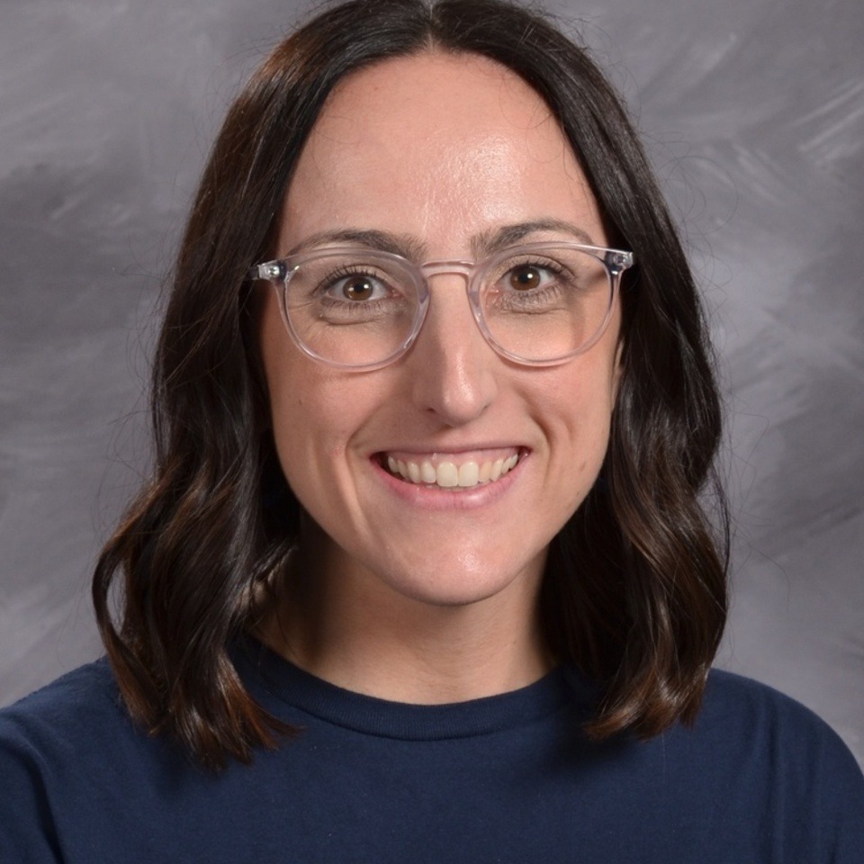 A smiling woman with short brown hair, wearing glasses