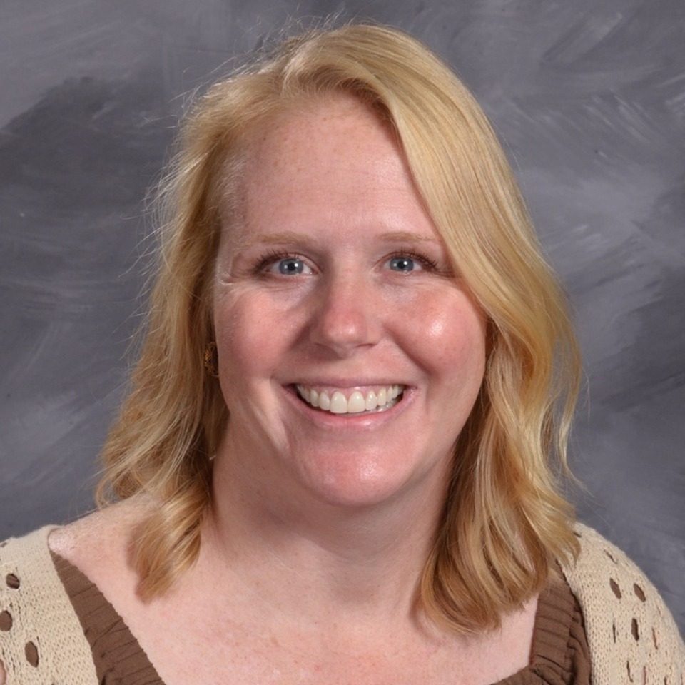 women with short blond hair, brown and tan shirt, on grey background