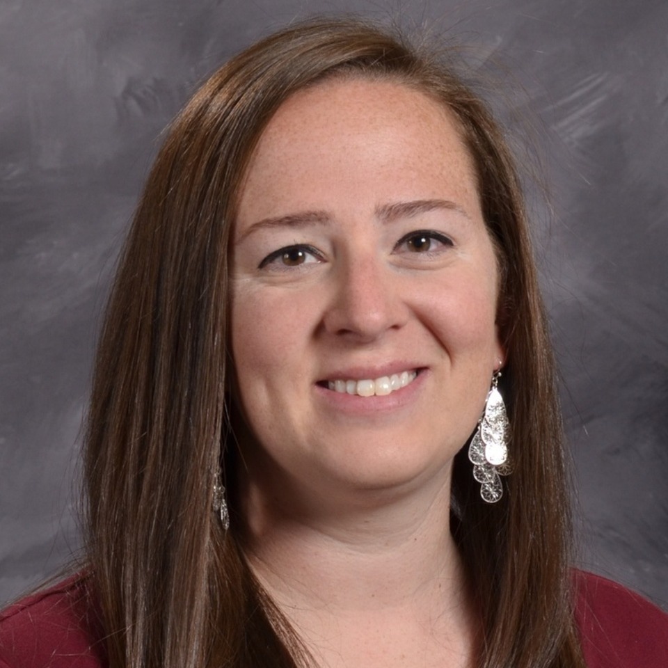 women smiling with long brown hair on grey background