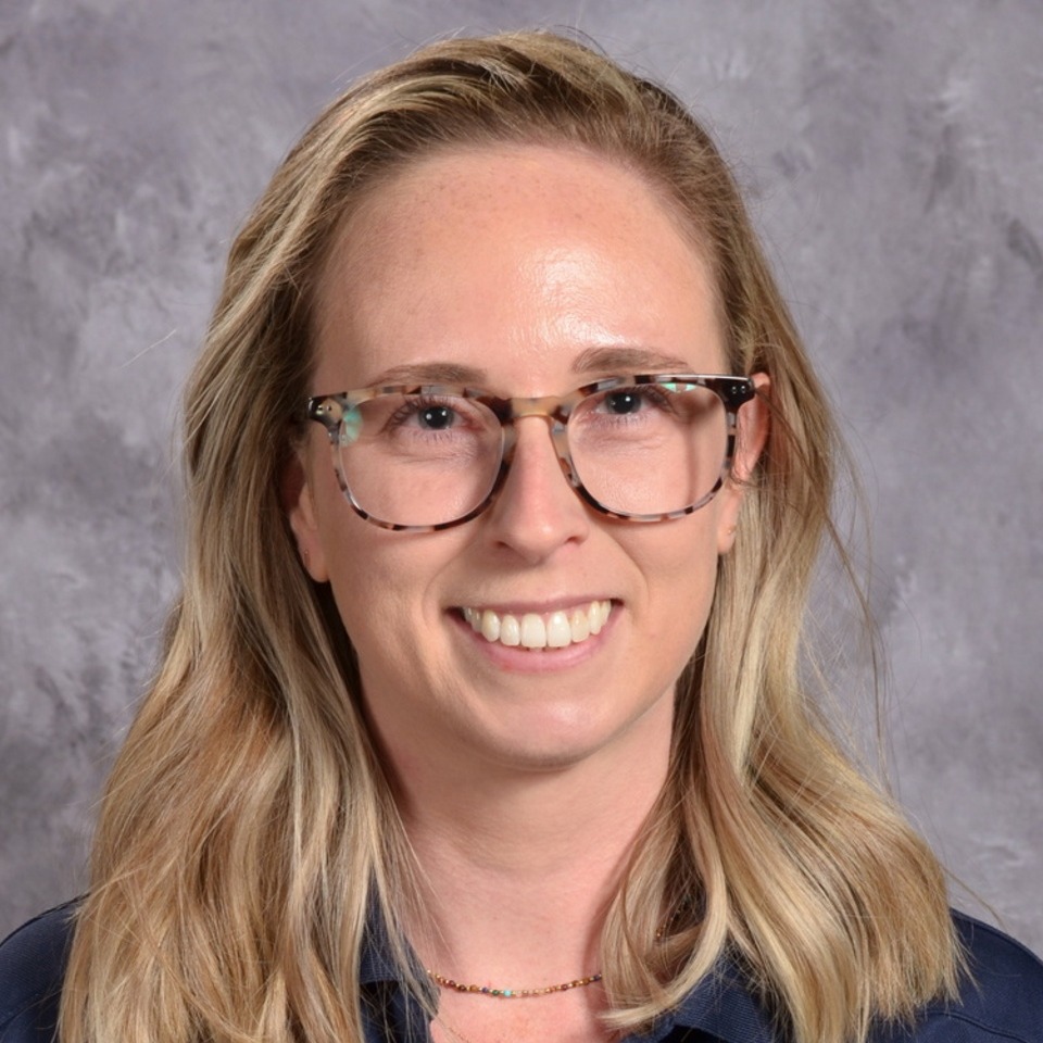 A women smiling with long blonde hair, wearing glasses, grey background