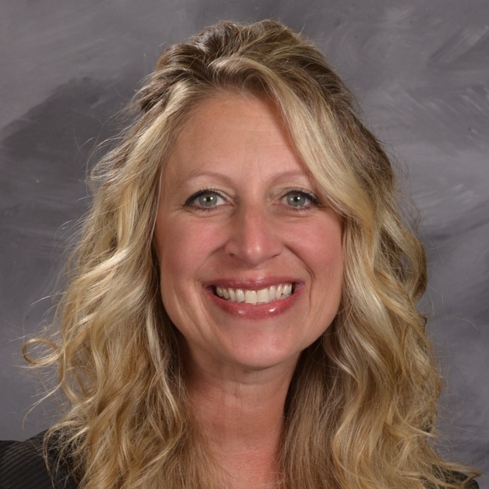 A women smiling with blonde wavy hair, grey background