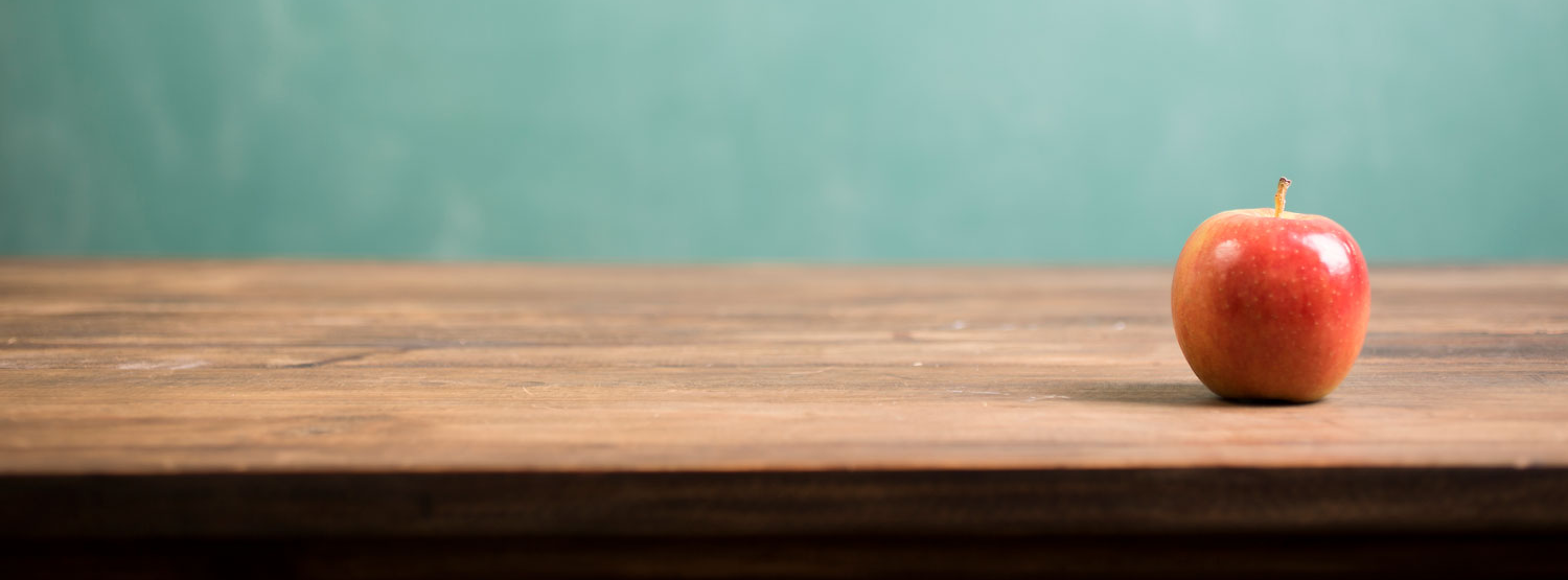 apple on desk with chalkboard in the background