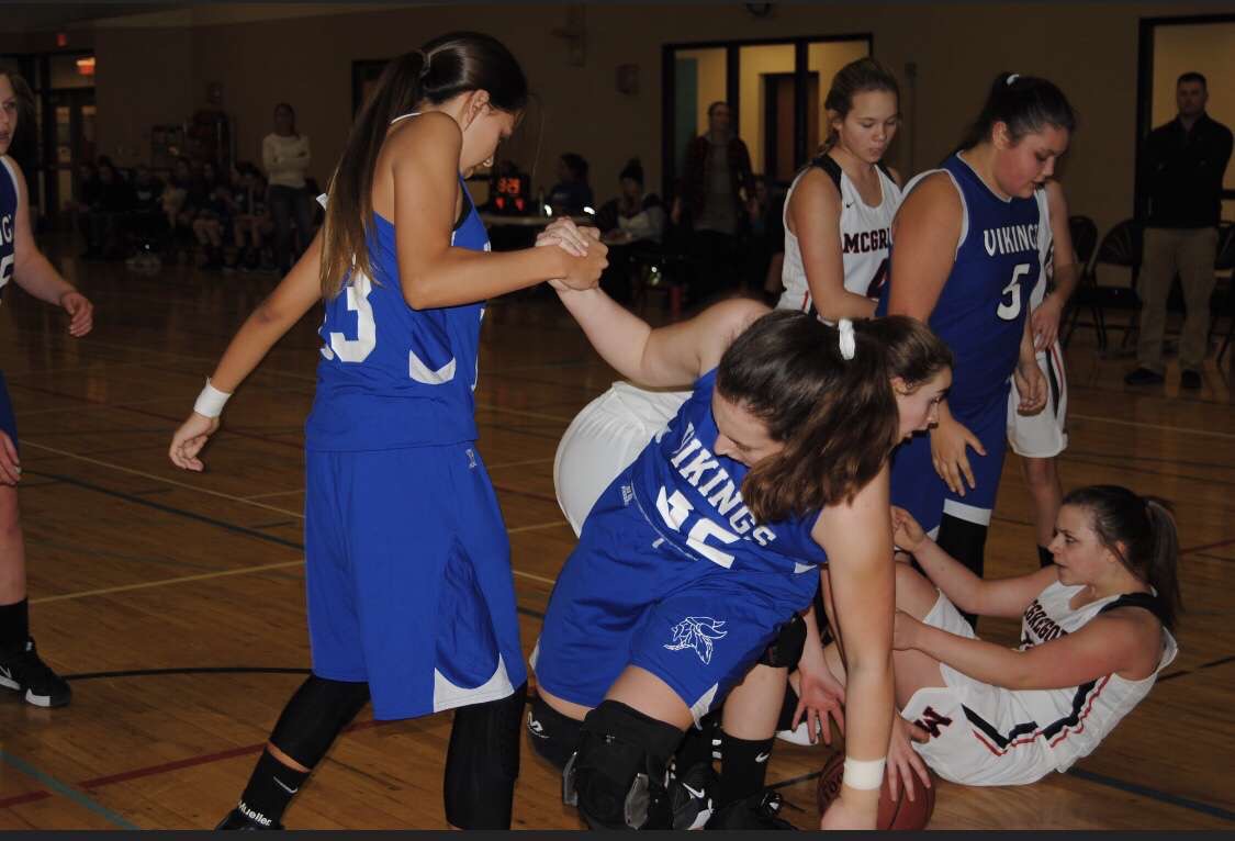 Girls basketball game. Helping each other up. 