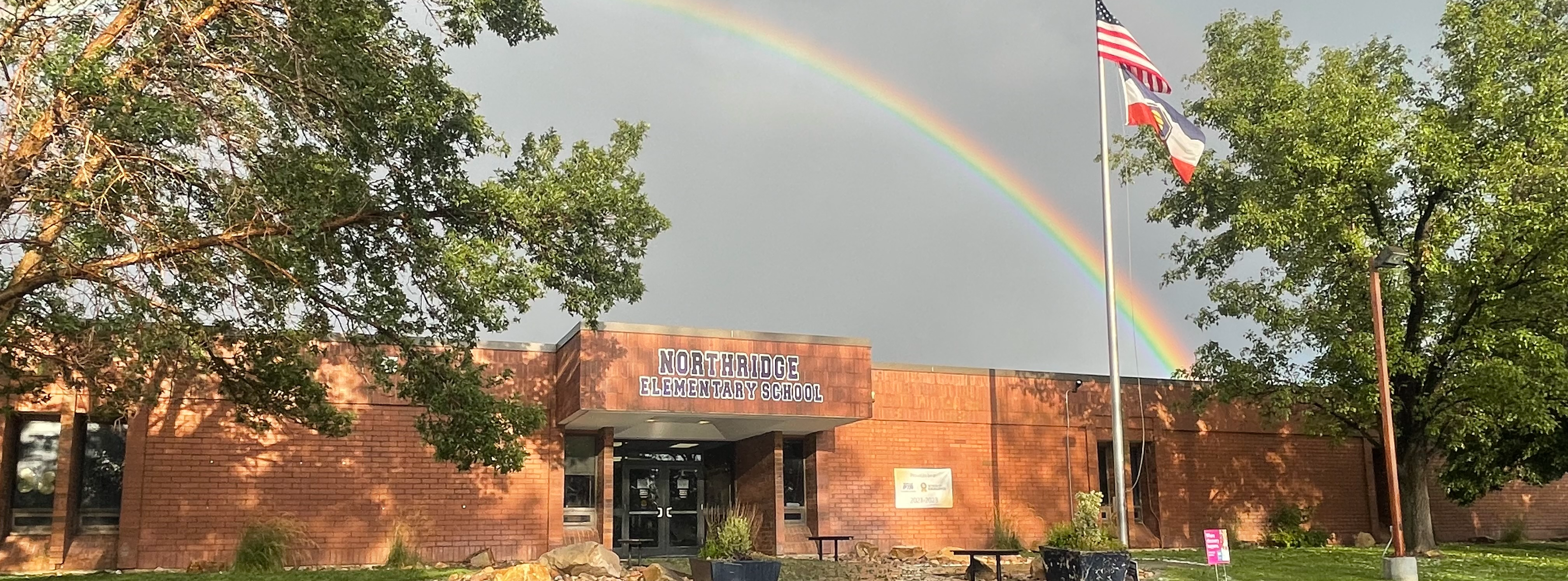 school building with a rainbow above it