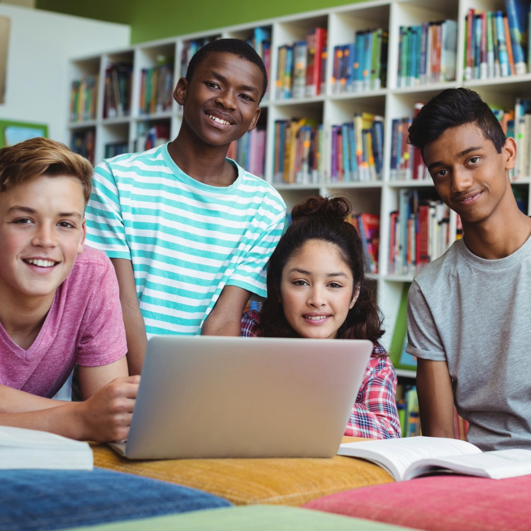 Group of teen students studying together in a library