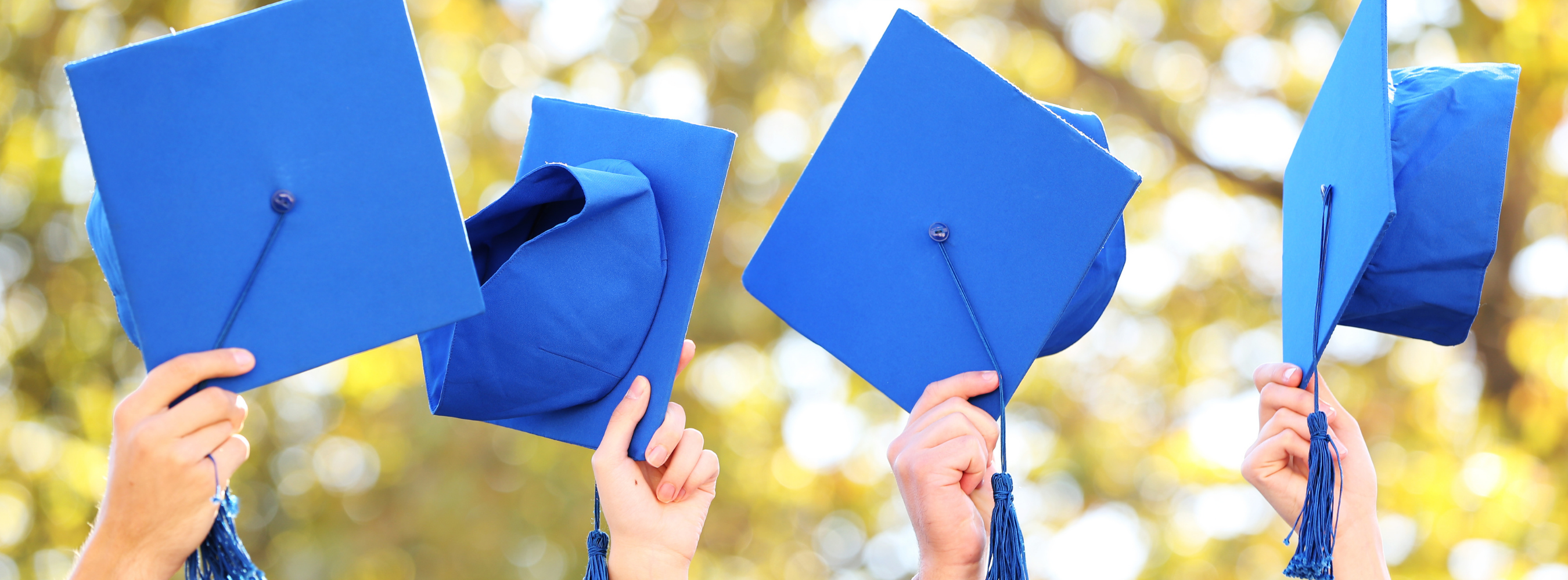 a picture of students holding up graduation caps to celebrate graduating