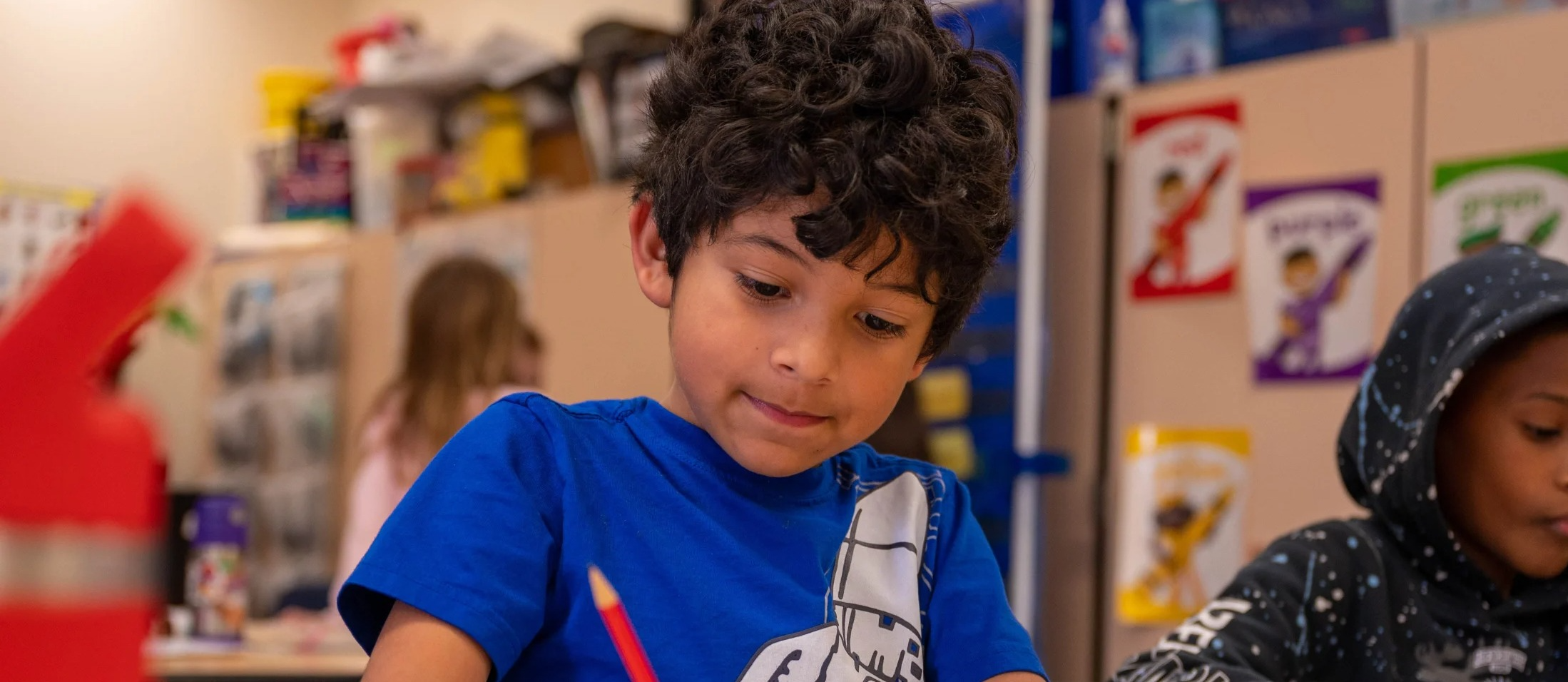 A boy using a pencil to write in a classroom