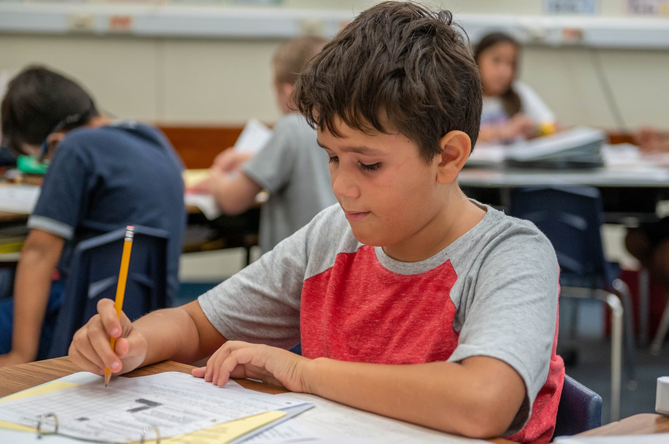 boy writing with pencil on paper 