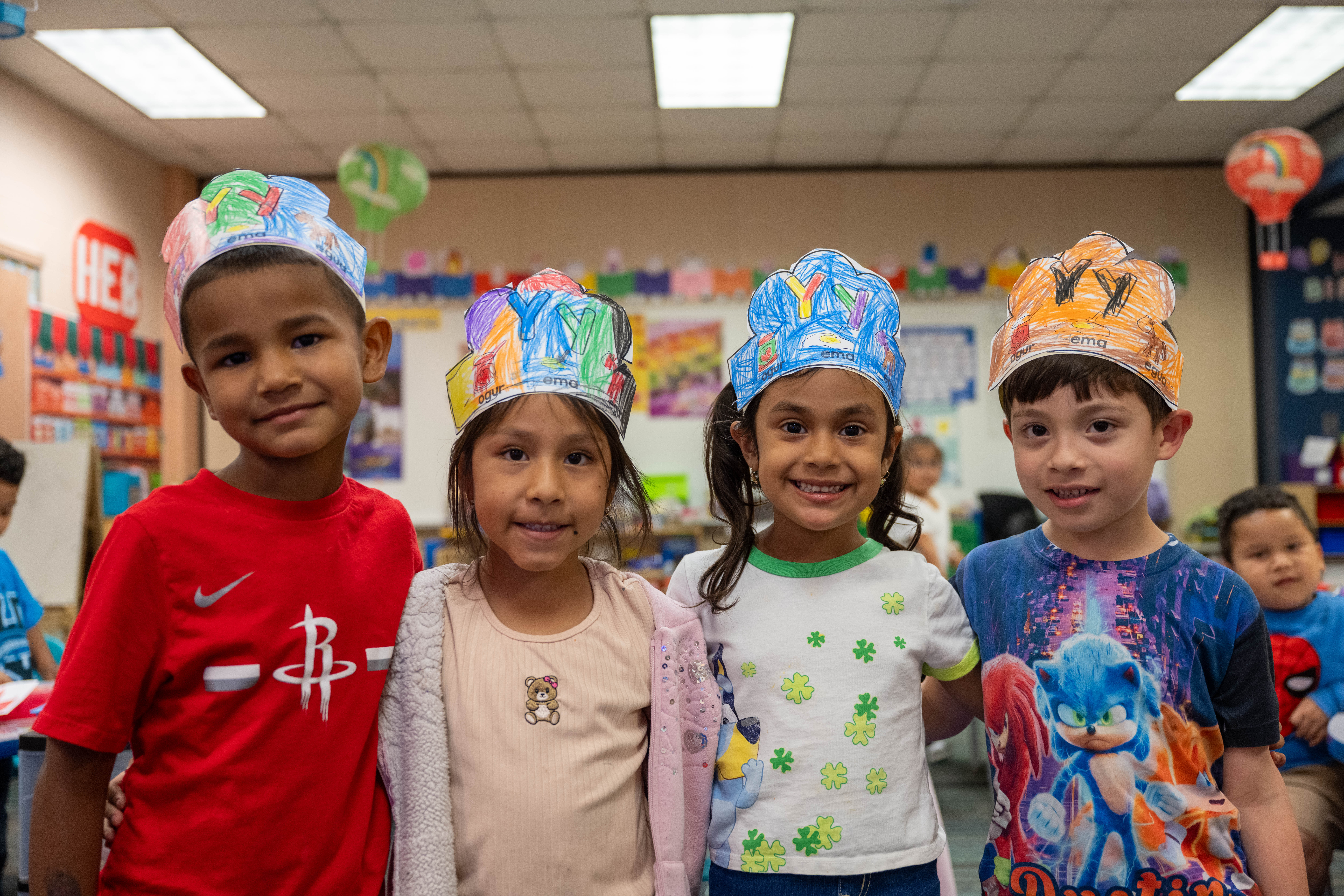 Four students posed side by side with letter crowns on